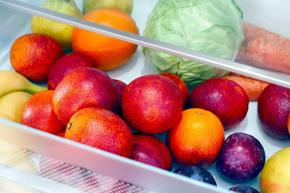Fresh, whole fruit and vegetables in a refrigerator crisper drawer