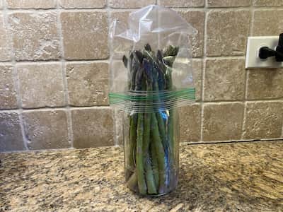 Bunch of asparagus standing in an inch of water in a mason jar, with a plastic baggie over the top, to keep them fresh.