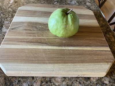 Picture of a guava on a wooden cutting board.
